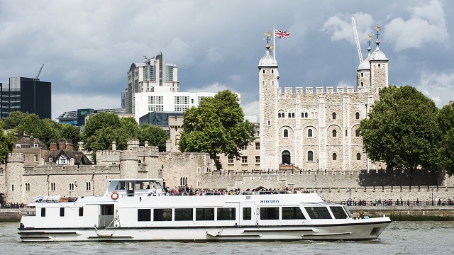 A white boat on Thames in front of Tower of London.