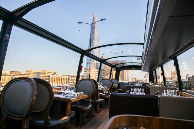 The shard is visible through the glass roof of a dining tour bus.
