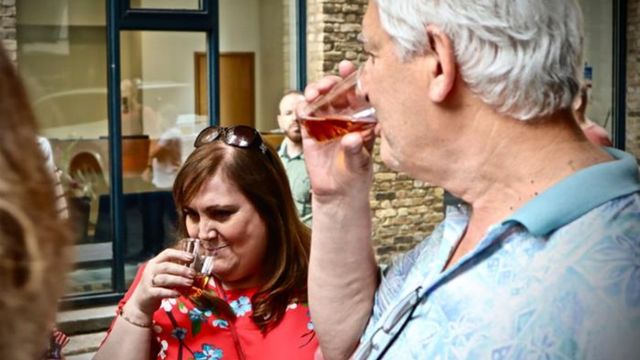 A man and woman smell and drink a glass of beer on a borough market food tour. 