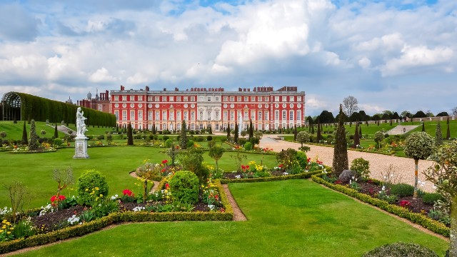 View of Hampton Court Palace and its gardens on a cloudy day.