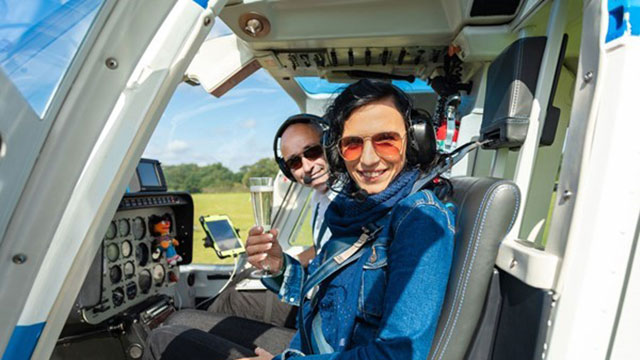 Une femme est assise sur le siège du copilote, à côté du pilote, avec une coupe de champagne.
