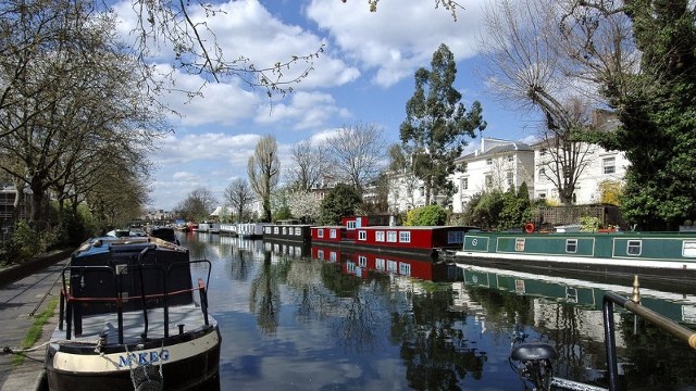 Looking along a canal, with canal boats on both sides of the canal, on a bright day.