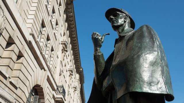 Sherlock Holmes statue outside Baker Street Station on a clear London day.