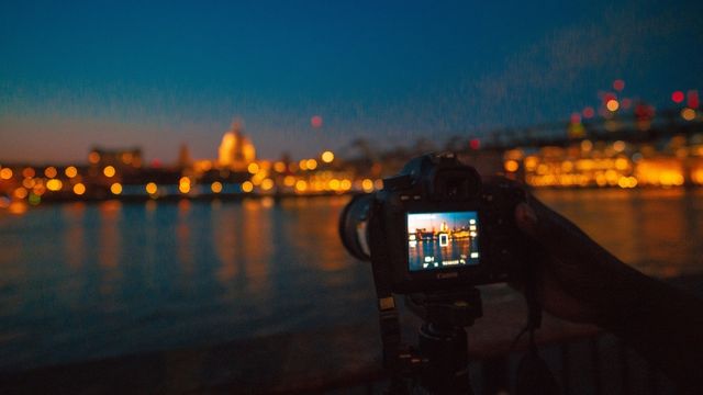 A camera takes a photo of the millennium bridge in london at night.