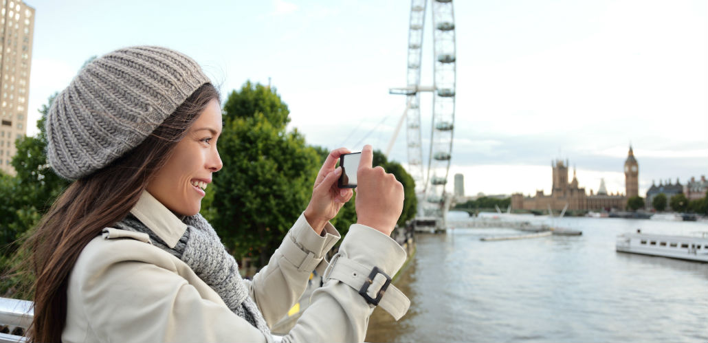Woman taking a picture with the London Eye skyline.
