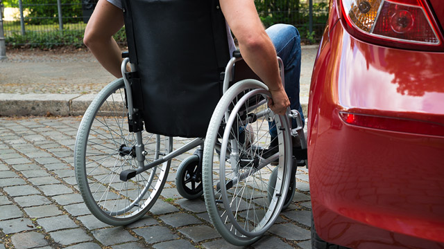 Wheelchair user next to a car on a cobblestone street in London