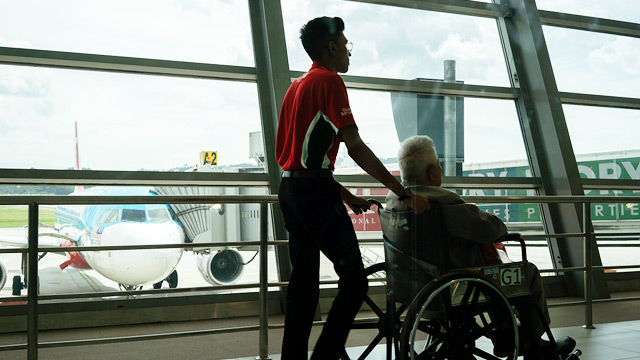 A man pushing another man in a wheelchair at London's Heathrow Airport