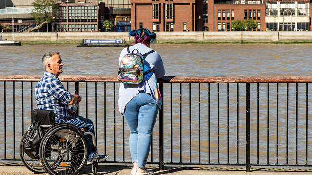 Man in a wheelchair talks to a woman on the South Bank in London