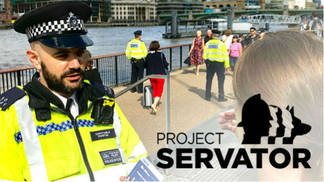 Un policier britannique est en conversation avec une personne aux cheveux longs châtains, au bord d’un plan d’eau.