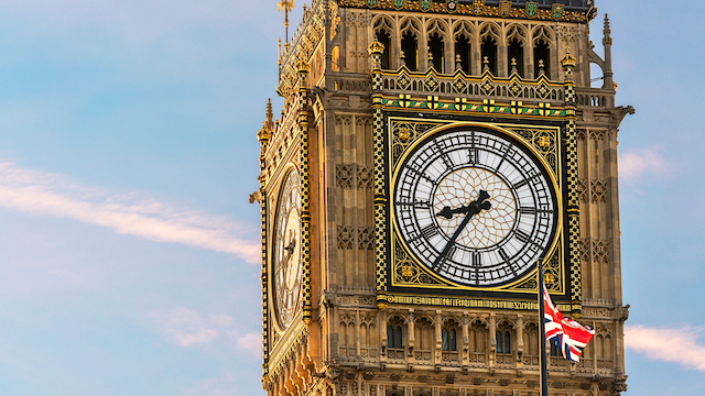 British Union flag in front of the clock face of Big Ben in London on a sunny day