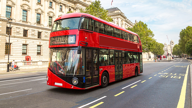 Un bus rouge à deux étages circulant dans Londres par une journée ensoleillée.