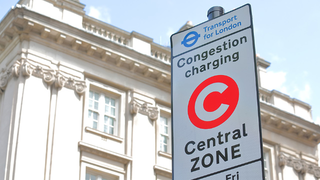 Sign in front of an ornate building in central London that reads, "Congestion charging central zone"