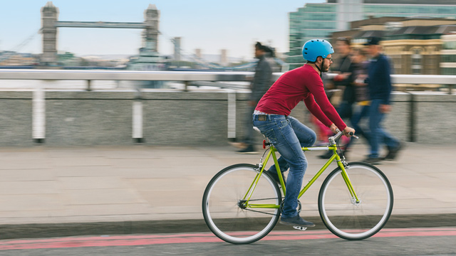 Man cycling over London Bridge with Tower Bridge in background