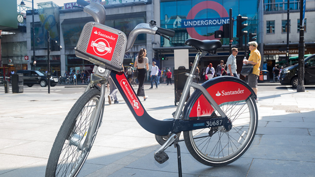 A Santander Cycle bicycle with an Underground station in the background.