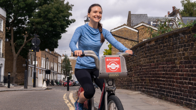 Woman rides a Santander Cycle hire bike on a street in London