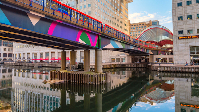 A DLR train pulls into Canary Wharf station in London on a sunny day