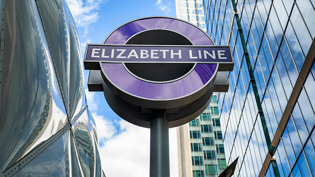Panneau rond de la ligne Elizabeth devant des gratte-ciel à Londres par une journée ensoleillée.