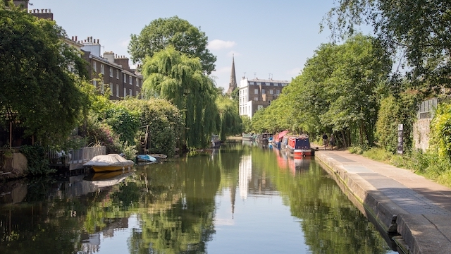 Calm waters in the canal reflect the trees and buildings of the Little Venice neighbourhood of London