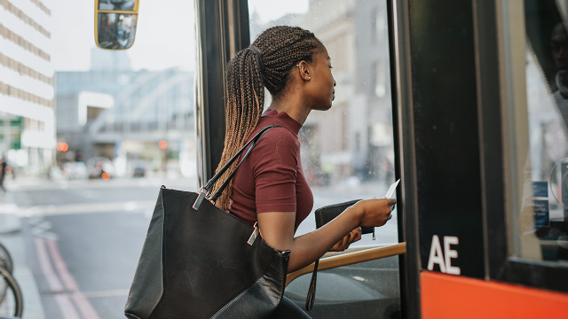 Young Black woman boarding a London bus.