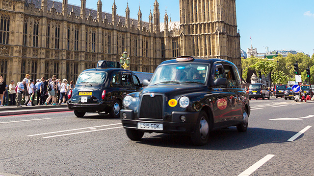Two black cabs wait in front of a theatre for passengers in London at night