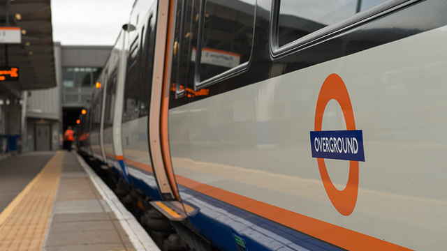 London Overground train waiting at a platform on a grey day.