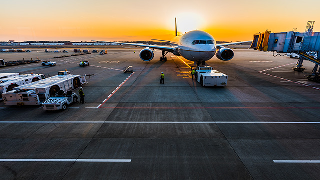 Avion atterri sur le tarmac de l'aéroport d'Heathrow avec le coucher de soleil en arrière-plan.