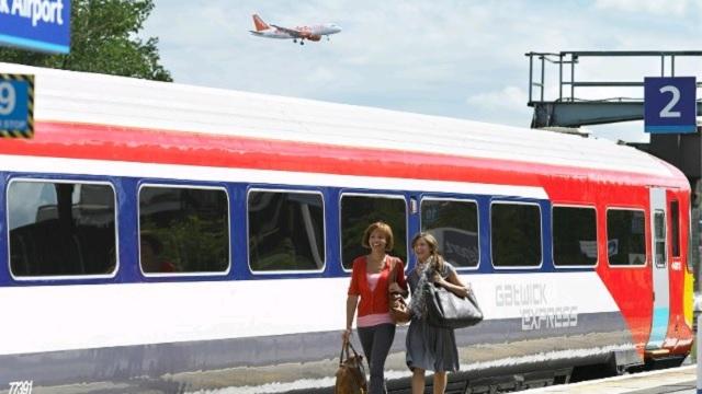 Two women walk past a Gatwick Express train.