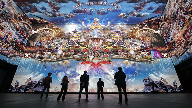 A group stands in front of a screen displaying a 360 degrees collage of various film clips.