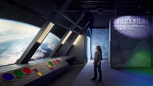 A woman stands on a observation deck at the Science Museum looking at Planet Earth from space.