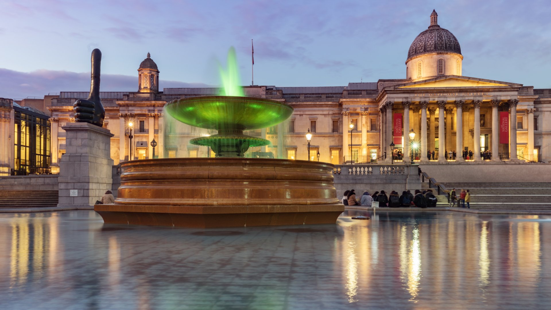 London National Gallery and Trafalgar Square and one of its fountains at dusk.