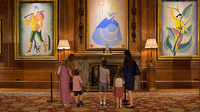 Zwei Frauen und drei Kinder betrachten die Pantomime-Bilder an der Wand des Waterloo-Saals. 
