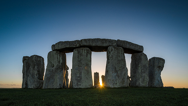 Stonehenge at sunrise, with the sun glinting between the stones.