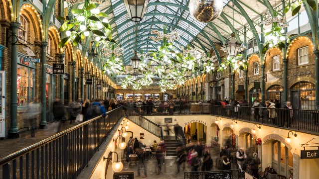 Mistletoe chandeliers, mirror balls and lights sparkle above crowds in Covent Garden's market building at Christmas