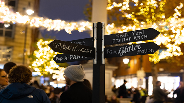 In Seven Dials befindet sich ein Wegweiser mit verschiedenen Weihnachtsaktivitäten, die festlich beleuchtet sind.