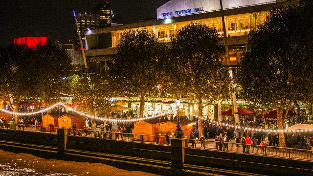 Garlands of Christmas lights illuminate the riverside area of the South Bank with wooden chalets in front of the Royal Festival Hall