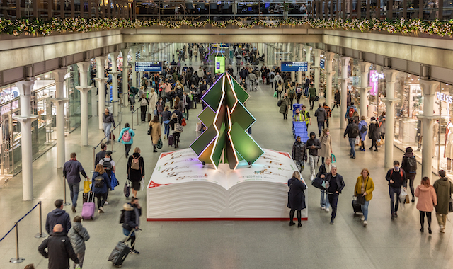 People walk by a Christmas tree installation at St Pancras International train station in London