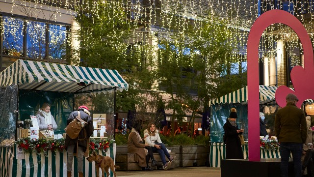 Market stalls operating under strings of hanging twinkly lights.