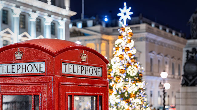 A red telephone box in front of an illuminated Christmas tree at Christmas time in London