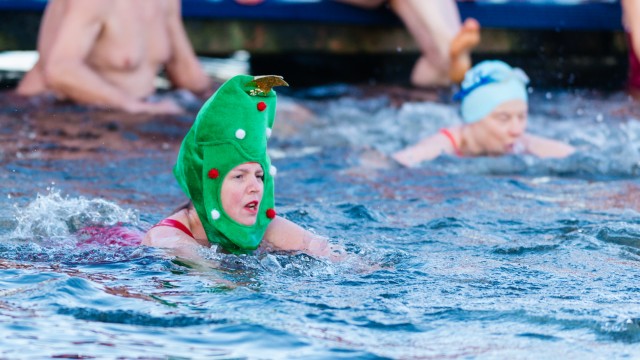 Eine Frau, die beim Schwimmen eine grüne Weihnachtsdekoration auf dem Kopf trägt. Nachweis: Serpentine Swimming Club.