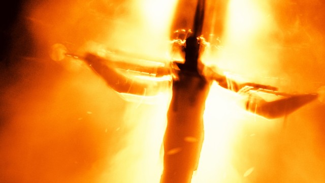 See Jesus Christ Superstar at Regent's Park Open Air Theatre. Image courtesy of Jo Allan PR. Blurry image of Jesus on the cross during a stage performance of Jesus Christ Superstar.