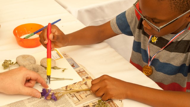 A child creating art with flowers and paint.