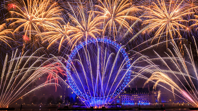 Ein buntes Silvesterfeuerwerk über dem mit blauen Lichtern beleuchteten London Eye
