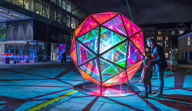 Brightly lit art installation titled Dichroic Sphere by Jakob Kvist at night near Southbank Centre in London
