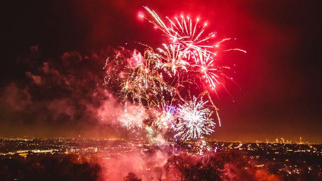 Red and white fireworks explode near Alexandra Palace at night, with the London skyline in the background.