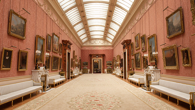 A long gallery with pink walls lined with framed paintings.