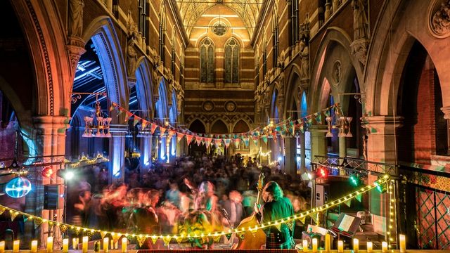 People dance together to scottish music at a church with tartan decorations on burns night london.