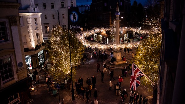 Twinkling Christmas lights circle the iconic roundabout in Seven Dials above crowds of people