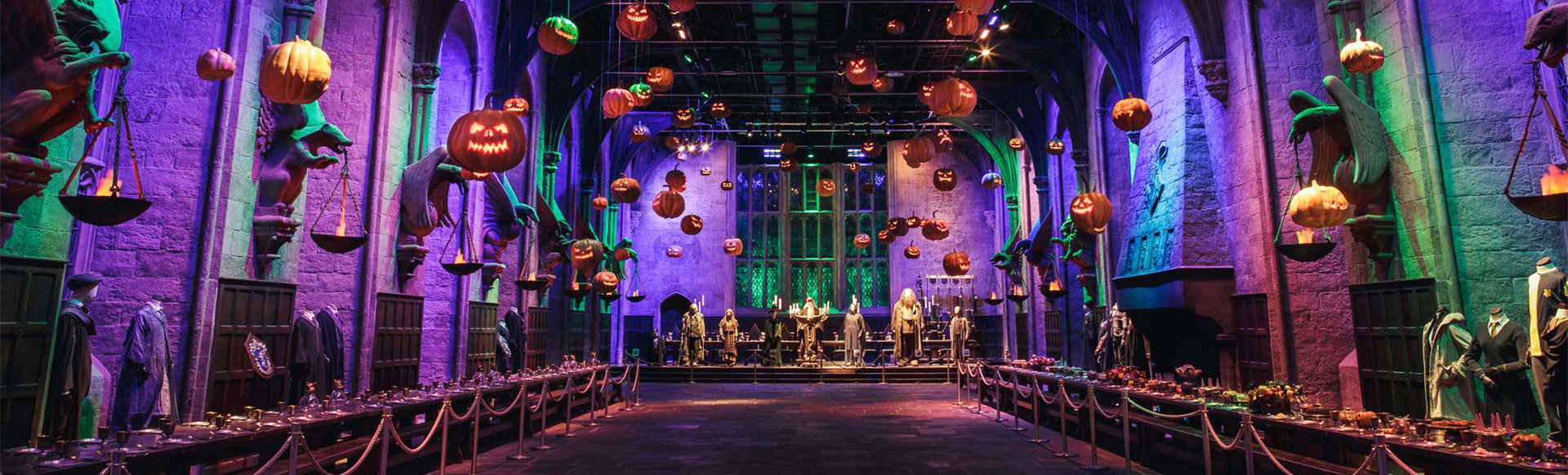 The Great Hall Harry Potter film set is filled with floating pumpkins and purple light for Halloween. 