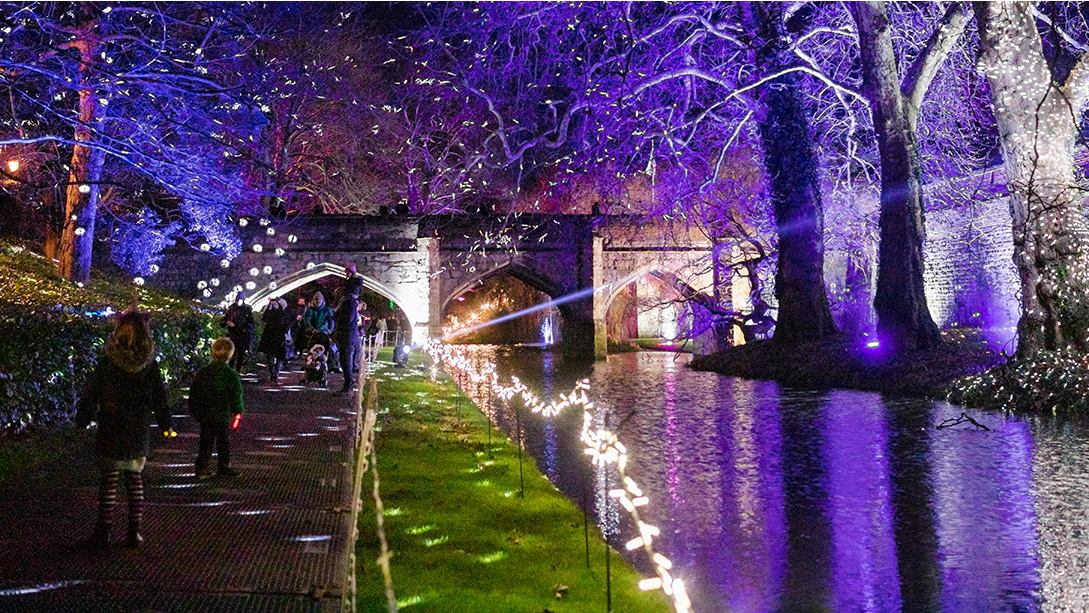 People walking along the river and light illuminations at Enchanted Eltham Palace