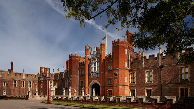 The entrance to Hampton Court Palace, surrounded by trees on a sunny day